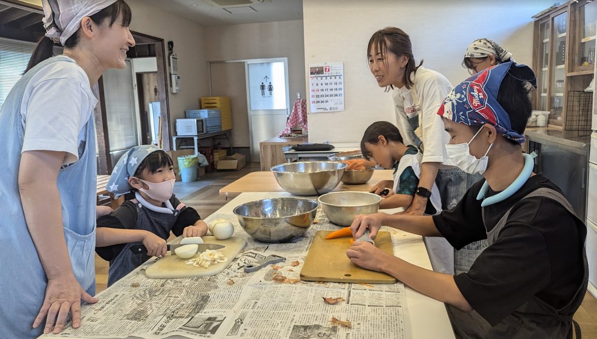 子どもと大人が一緒に、野菜を切って調理している様子